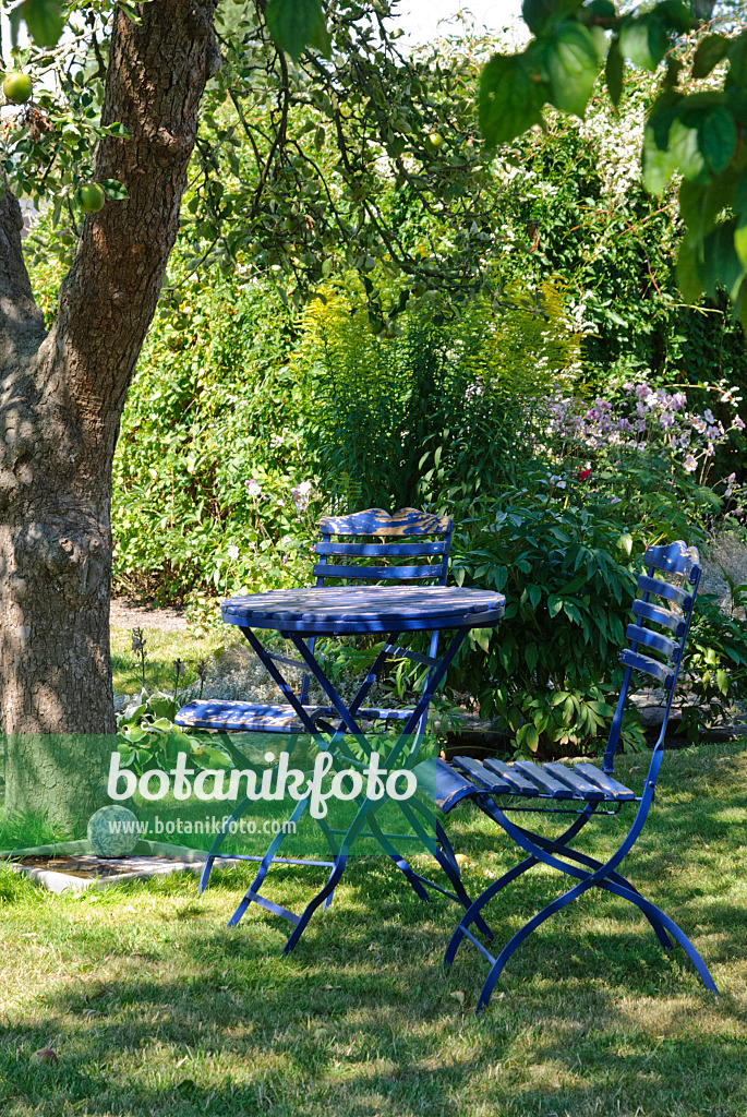 475276 - Blauer Gartentisch mit zwei Klappstühlen unter einem Apfelbaum