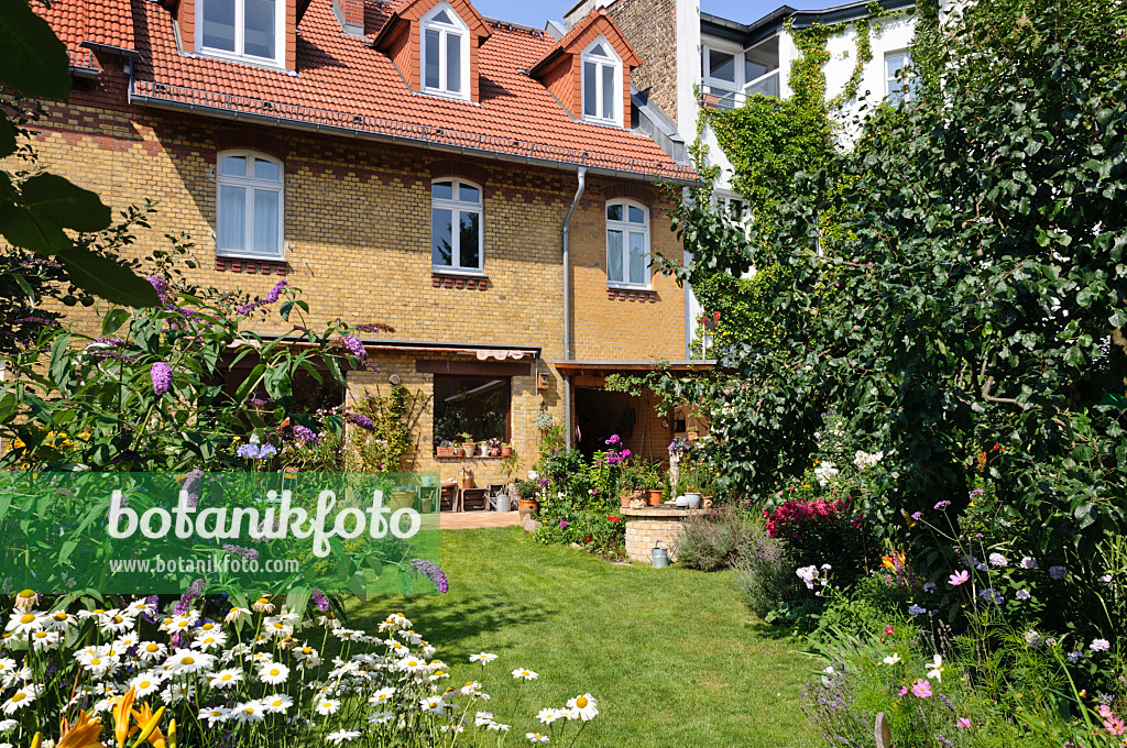 474346 - Hofgarten mit Staudenbeeten, Rasenfläche und Terrasse mit Kübelpflanzen