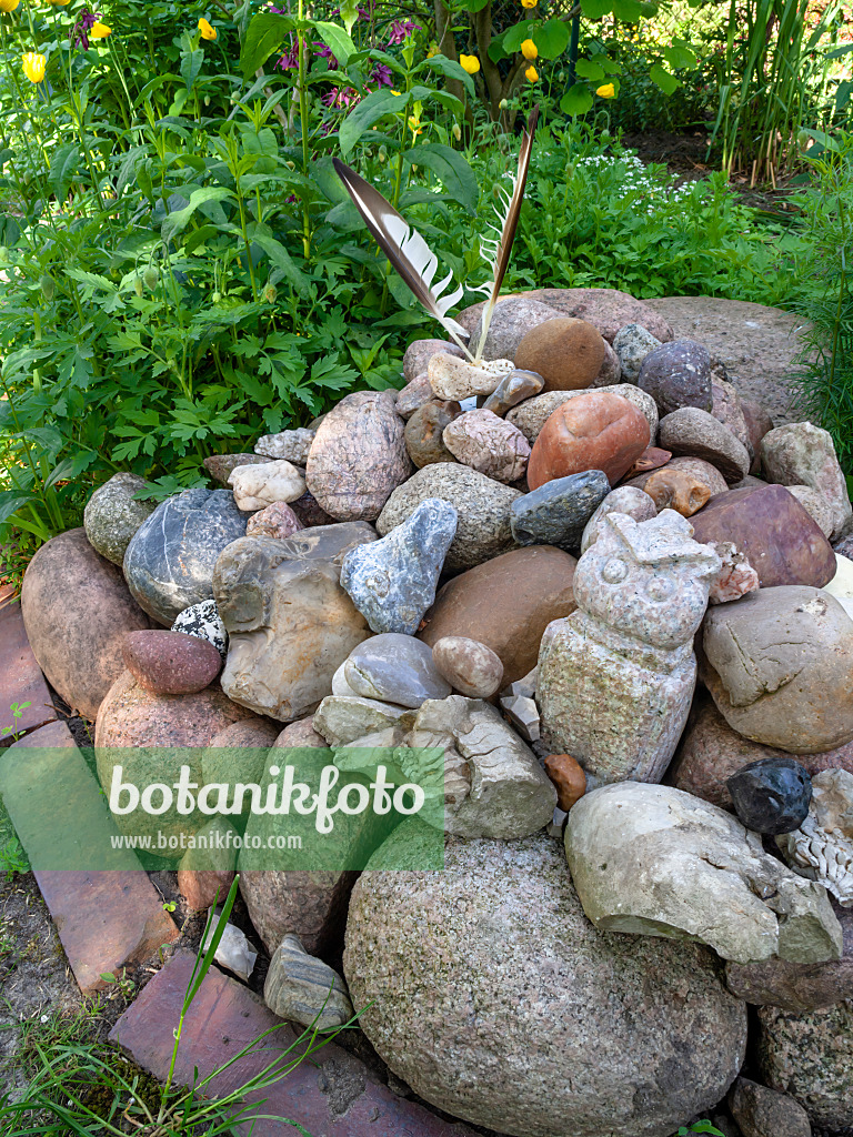 460099 - Clusters of stones from large boulders, stone sculptures and two bird feathers in a garden