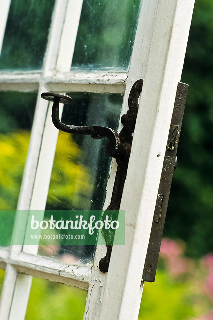 381096 - Muntin door with glass panes and iron handle of an old garden house