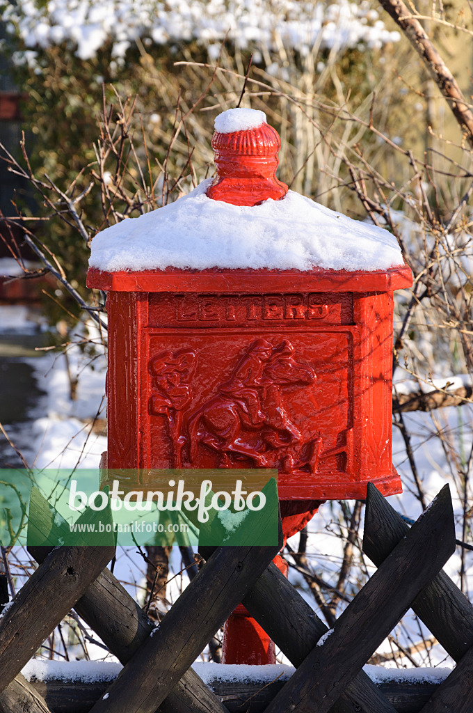 468010 - Snow-covered red letterbox in front of a wooden fence