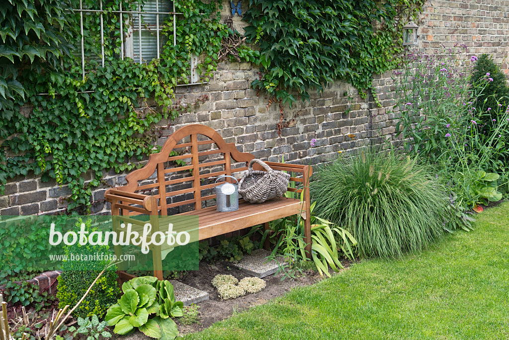 536195 - Wooden bench with watering can and basket in a perennial garden