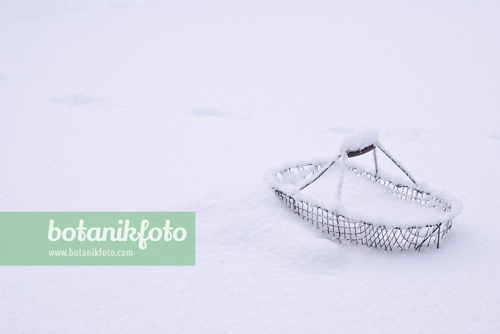 517016 - Panier en fil de fer avec anse en bois dans la neige profonde