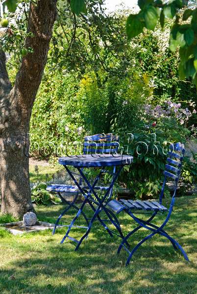 475276 - Blauer Gartentisch mit zwei Klappstühlen unter einem Apfelbaum