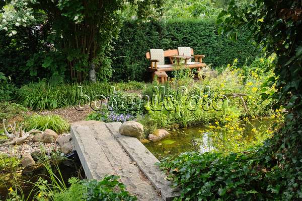 486018 - Gartenbank an einem Teich mit Steinbrücke