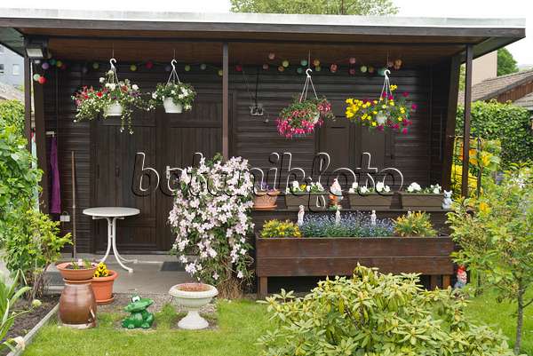 532005 - Gartenlaube mit bepflanzten Blumenampeln und Blumenkästen