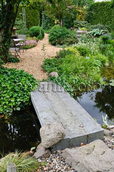 473082 - Gartenteich mit Steinbrücke und Sitzgelegenheit zum Ausruhen in einem gepflegten Park