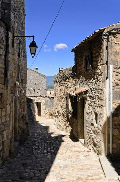 557162 - Gepflasterter Weg zwischen Häusern mit Feldsteinmauern und eiserner Laterne, Lacoste, Provence, Frankreich