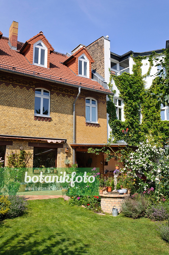 474345 - Hofgarten mit Staudenbeeten, Rasenfläche und Terrasse mit Kübelpflanzen