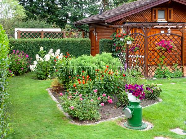 475245 - Abri de jardin en bois et parterres de fleurs dans un jardin familial