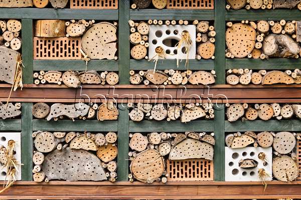 473185 - Aide à la nidification des insectes avec des briques perforées remplies de paille, de branches et de troncs d'arbres dans une grille en bois