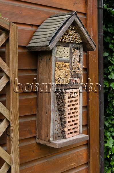 521084 - Aide à la nidification des insectes avec des briques perforées, des branches et de la paille sur un mur de planches