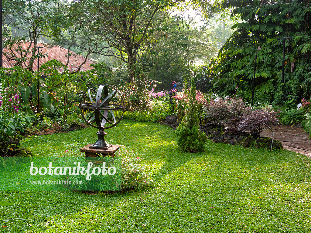 411187 - Art object on stone pedestal in a tropical garden, Singapore