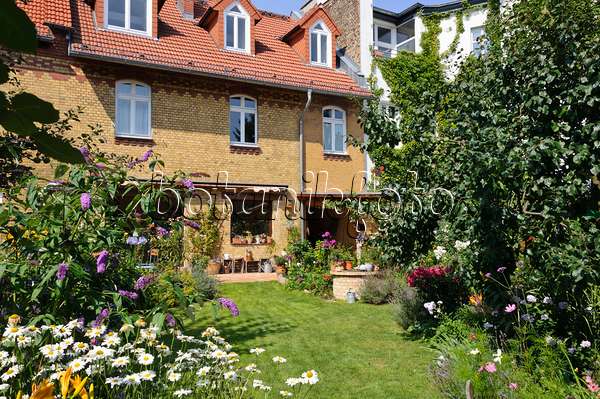 474346 - Cour-jardin avec parterres de vivaces, pelouse et terrasse avec plantes en pot