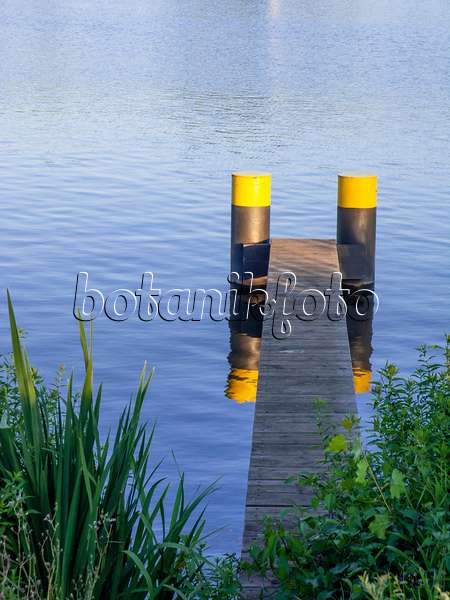 451018 - Jetée étroite faite de lattes de bois avec deux pontons peints en noir et jaune dans une eau bleue