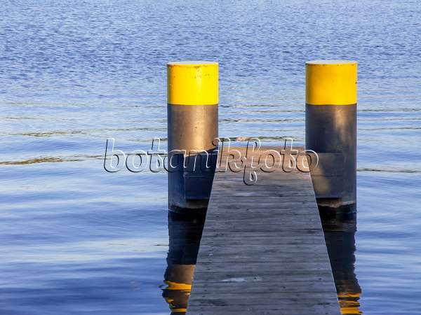 451019 - Jetée étroite faite de lattes de bois avec deux pontons peints en noir et jaune dans une eau bleue