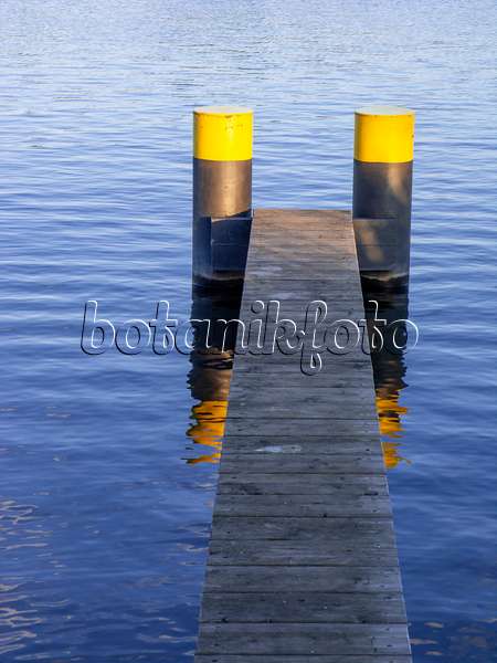451020 - Jetée étroite faite de lattes de bois avec deux pontons peints en noir et jaune dans une eau bleue
