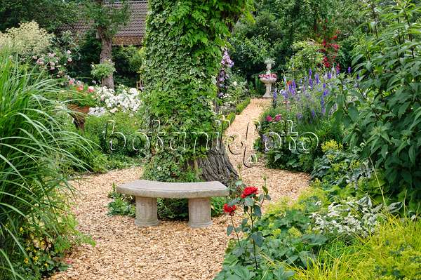474090 - Petit banc en pierre dans un jardin de plantes vivaces