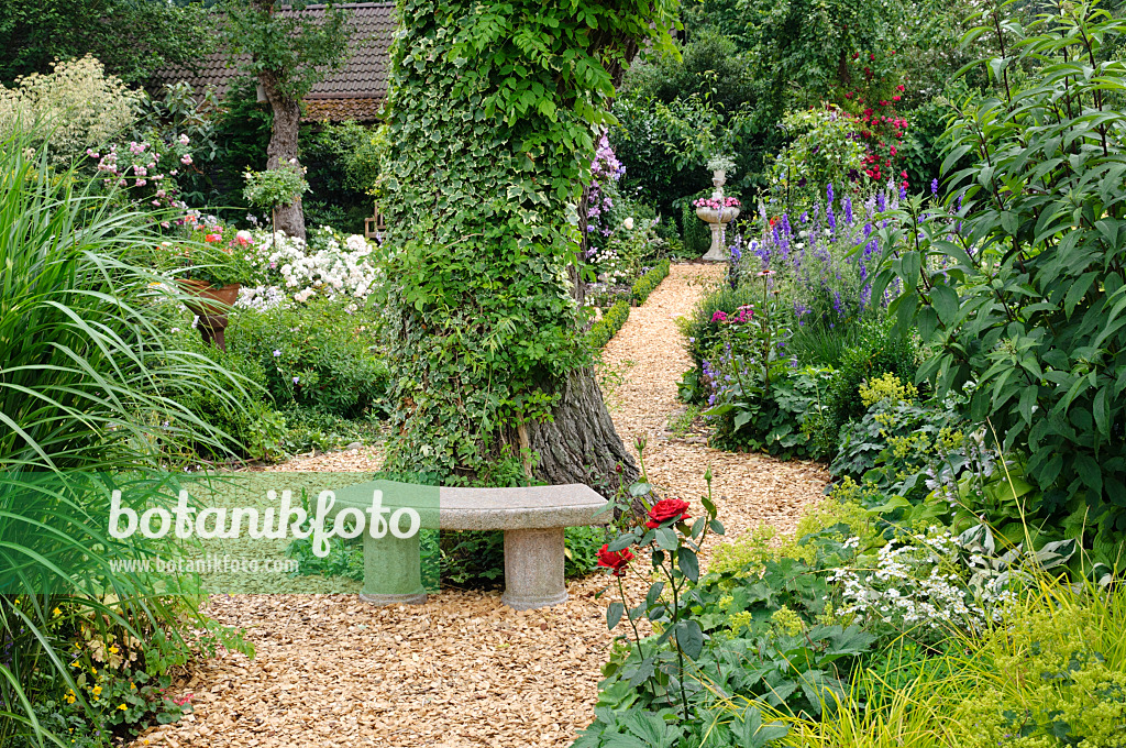 474090 - Petit banc en pierre dans un jardin de plantes vivaces