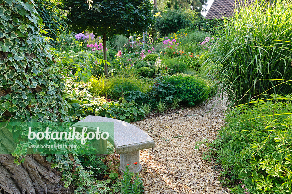 474448 - Petit banc en pierre dans un jardin de plantes vivaces