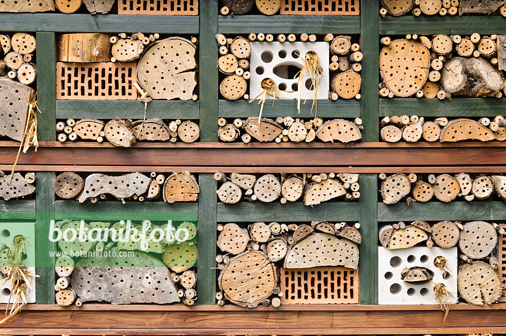 473185 - Aide à la nidification des insectes avec des briques perforées remplies de paille, de branches et de troncs d'arbres dans une grille en bois