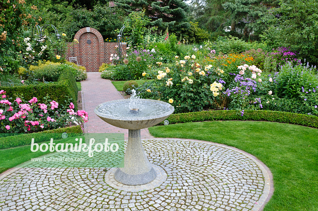474054 - Fontaine en granit dans un jardin de roses