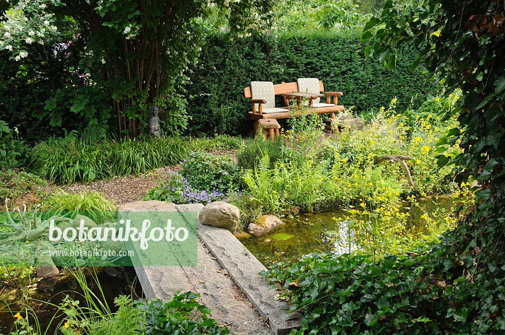 486018 - Garden bench at a pond with a stone bridge