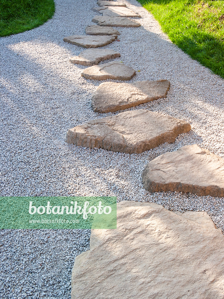 416075 - Garden path made of individually laid hewn stone slabs in a gravel bed