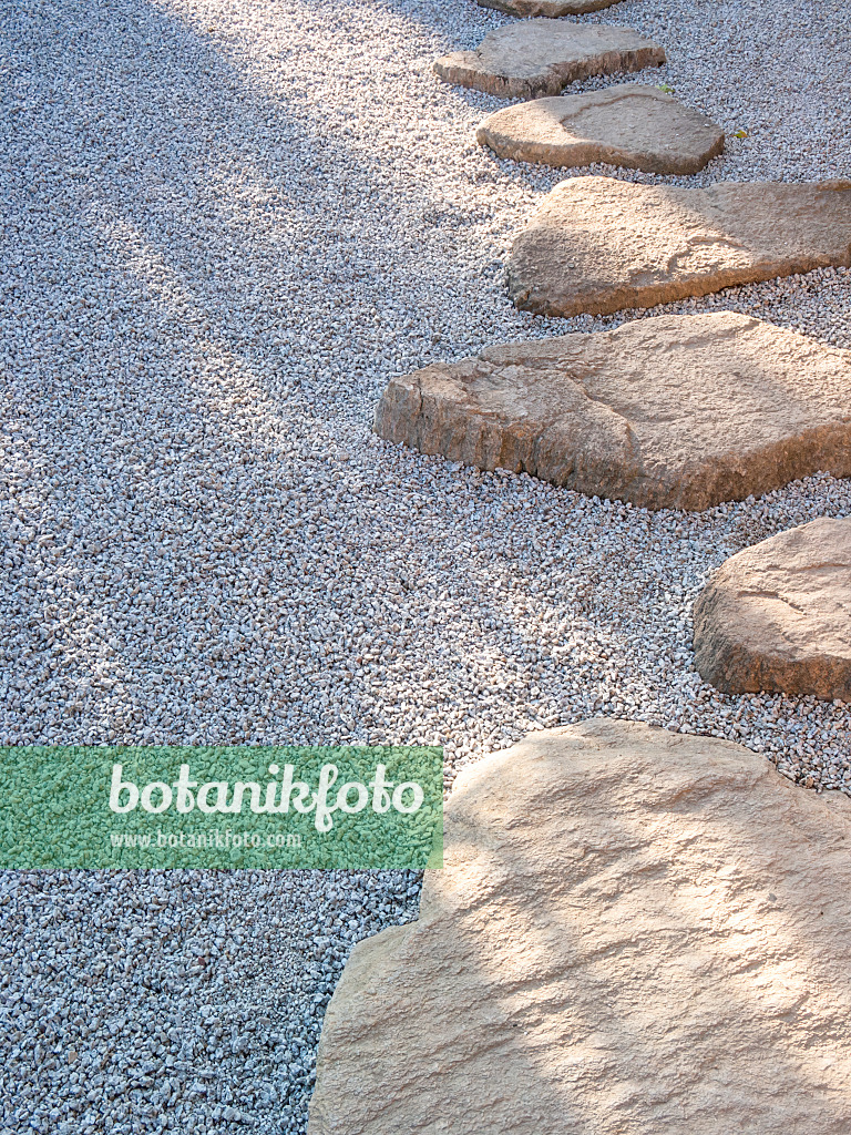 416076 - Garden path made of individually laid hewn stone slabs in a gravel bed