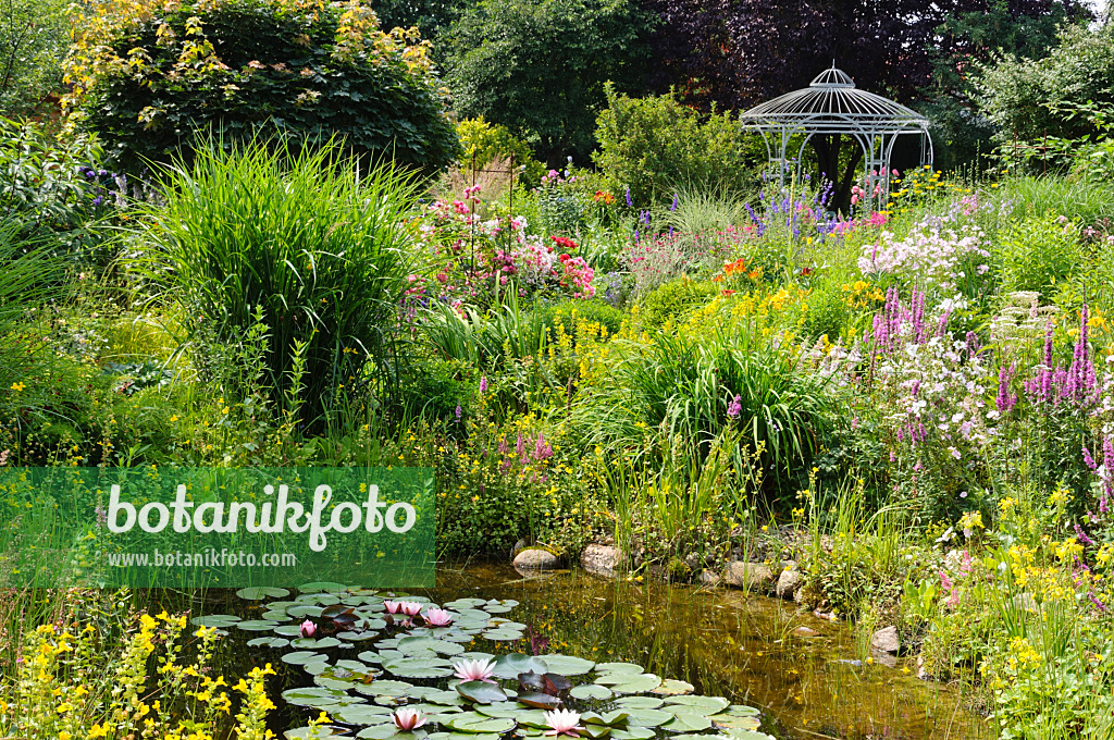 474103 - Garden pond in a rich flowering garden with pavilion