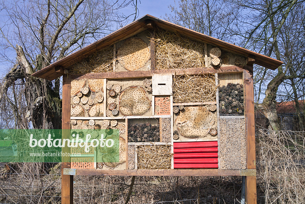 566083 - Grand hôtel à insectes avec un toit à deux pans et des rondins, des branches et des briques perforées, des pommes de pin et de la paille