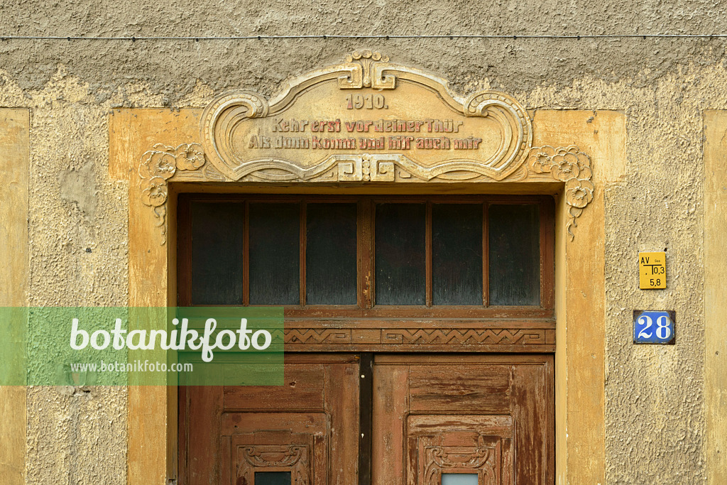 559034 - Old house entrance with double wooden door and saying of wisdom on a stone cornice, Görlitz, Germany