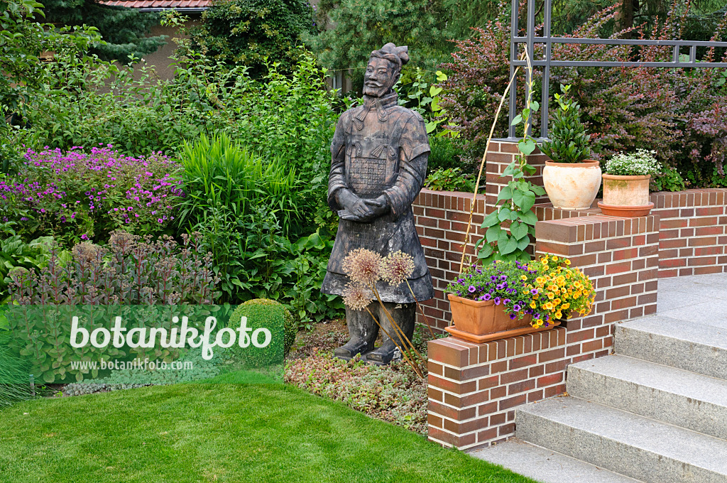 474061 - Perennial border with potted plants and reproduction of a Chinese clay warrior