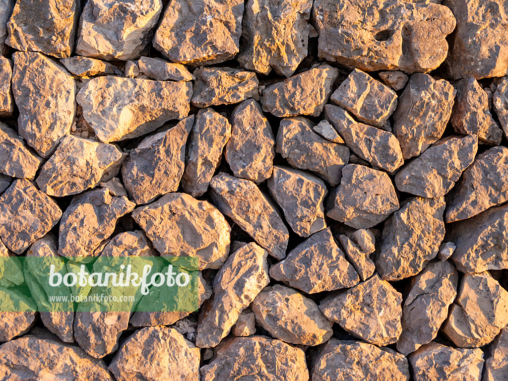 424042 - Stone wall made of randomly hewn stones in sunlight