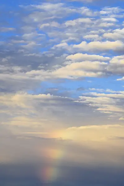 557090 - Altocumulus clouds under a blue sky with rainbow