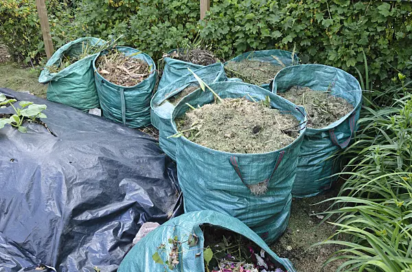 534040 - Bags with garden waste, next to them raised bed with foil as winter protection