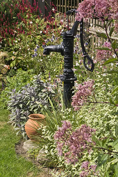 536196 - Beam pump and stoneware jar in a perennial garden