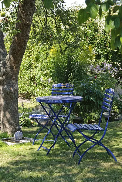 475276 - Blue garden table with two folding chairs under an apple tree