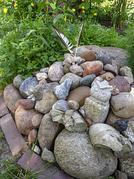 460099 - Clusters of stones from large boulders, stone sculptures and two bird feathers in a garden