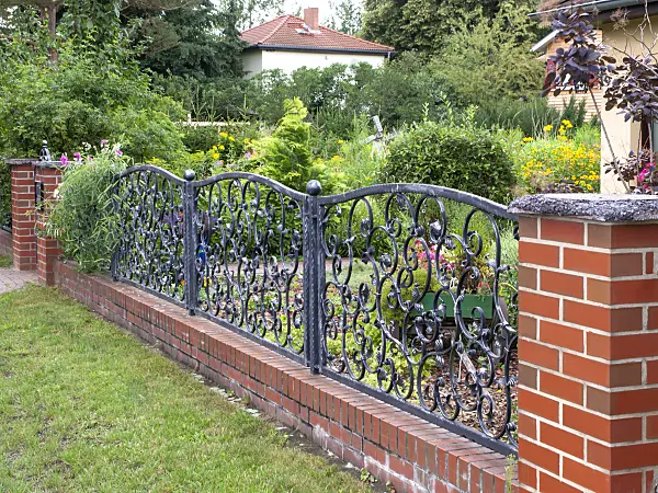 474422 - Curved metal fence on a brick wall in front of a flowering front garden