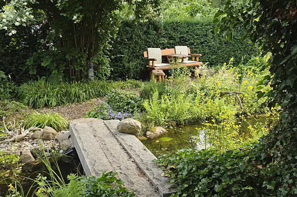 486018 - Garden bench at a pond with a stone bridge