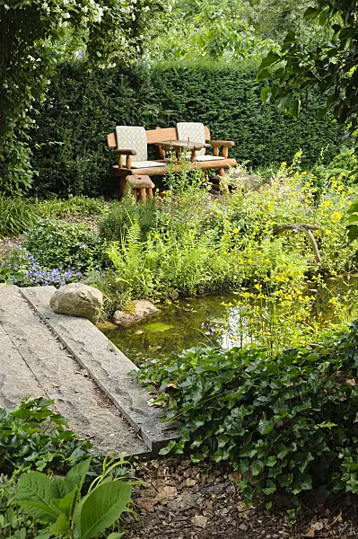 486019 - Garden bench at a pond with a stone bridge