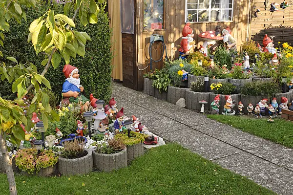 477005 - Garden gnomes in different sizes between a slab path and in front of an arbour in the allotment garden