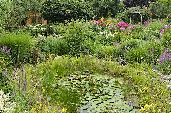 546053 - Garden pond in a rich flowering garden with pavilion