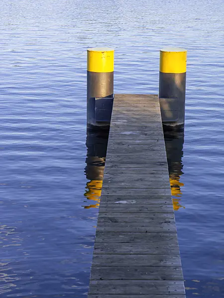 451020 - Narrow jetty made of wooden slats with two pontoons painted in yellow-black with blue water