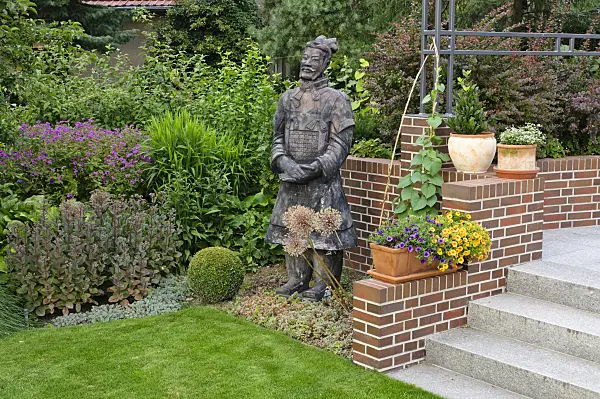 474061 - Perennial border with potted plants and reproduction of a Chinese clay warrior