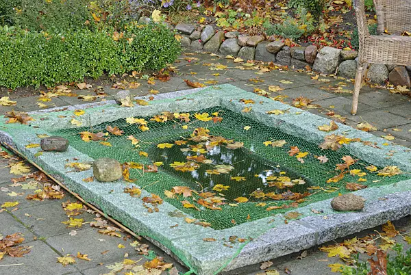 517007 - Protecting garden pond with a net against autumn leaves (3)