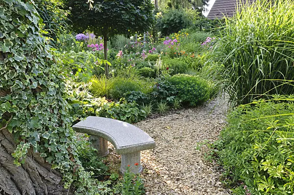 474448 - Small stone bench in a perennial garden