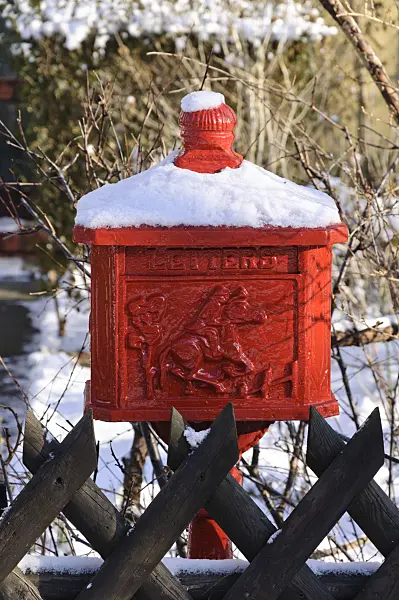 468010 - Snow-covered red letterbox in front of a wooden fence