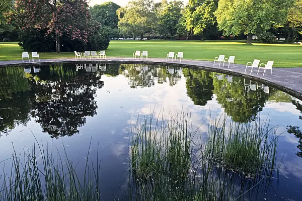 390112 - Water garden with mirrored water rondell and white relaxing chairs, Stadtpark, Hannover, Germany